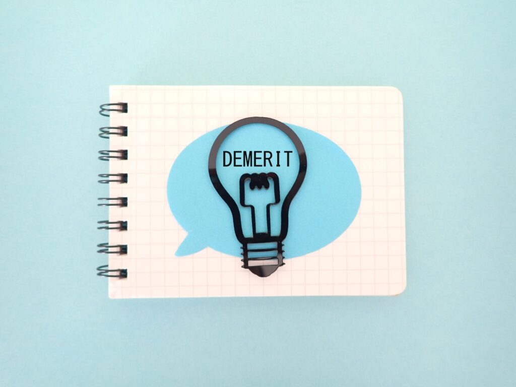 ノートにDEMERITデメリットの単語と電球